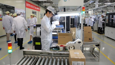 In this March 6, 2019, file photo, a staff member works on a mobile phone production line during a media tour in a Huawei factory in Dongguan, China.