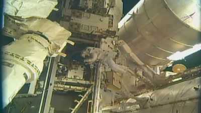 This photo, provided by NASA, shows astronauts Andrew Morgan and Nick Hague (not seen) installing a docking port outside the International Space Station, Wednesday, Aug. 21, 2019.
