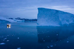 In this Aug. 15, 2019, file photo, a boat navigates at night next to large icebergs in eastern Greenland.