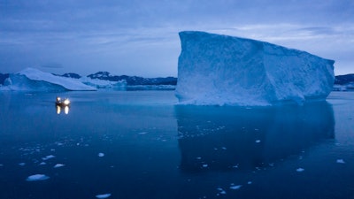 In this Aug. 15, 2019, file photo, a boat navigates at night next to large icebergs in eastern Greenland.