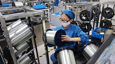 In this Aug. 14, 2019, photo, a woman works on a production line in a fiber optics factory in Nantong, China.