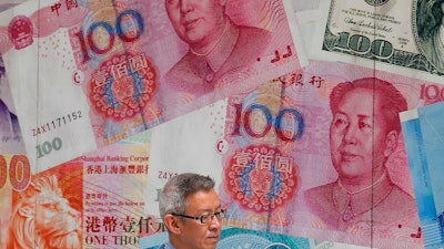 In this Aug. 6, 2019, file photo, a man walks by a money exchange shop in Hong Kong.