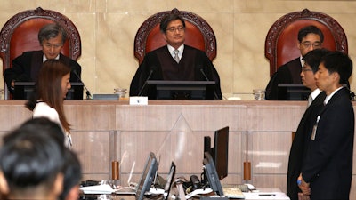 South Korean Chief Justice of the Supreme Court Kim Myeong-su, top center, sits with other justices upon their arrival at the Supreme Court in Seoul, Thursday, Aug. 29, 2019.