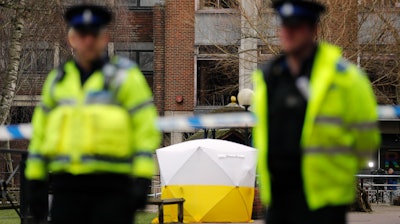 In this March 6, 2018 file photo, Police officers secure the area as a police tent covers the spot in Salisbury, England, where former Russian spy double agent Sergei Skripal and his daughter, Yulia, were found critically ill following exposure to a nerve agent. President Donald Trump is levying more sanctions on Russia in connection with the alleged 2018 poisoning of former Russian spy Sergei Skripal and his daughter, Yulia, in Salisbury, England.