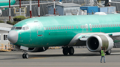 In this May 8, 2019, file photo a worker stands near a Boeing 737 MAX 8 jetliner being built for American Airlines prior to a test flight in Renton, Wash. Boeing is working on new software for the 737 Max that will use a second flight control computer to make the system more reliable, solving a problem that surfaced in June with the grounded jet, two people briefed on the matter said Friday, Aug. 2.