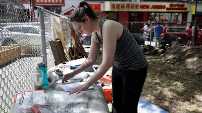 In this July 8, 2019 file photo Sarah Keklak, archaeology lab manager for the city of Boston, sorts samples at the first historical excavation, in Boston's Chinatown. The archaeological dig has been cut short after it turned up a 1980s music cassette, a toy dinosaur and other bric-a-brac. The city's Archaeology Program tweeted Tuesday, July 30, that it was wrapping up its three-week excavation at a vacant lot near the neighborhood's distinctive gateway because researchers have reached the water table, and it is unsafe to dig further.