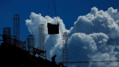 In this July 2, 2019, file photo a construction worker walks atop a building as a crane lifts a load over head in Miami. On Friday, Aug. 2, the U.S. government issues the July jobs report.