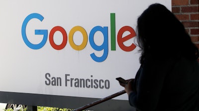 In this May 1, 2019, file photo, a person walks past a Google sign in San Francisco. A federal appeals court has rejected a settlement in a class-action lawsuit alleging that Google spied on users' online activity using tracking 'cookies,' even when privacy settings were set to prevent the snooping. A three-judge panel ruled Tuesday, Aug. 6, that a Delaware judge erred in approving the settlement in 2017.