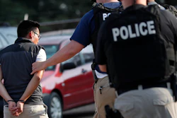 In this Aug. 7, 2019, file photo, a man is taken into custody at a Koch Foods Inc. plant in Morton, Miss. Unauthorized workers are jailed or deported, while the managers and business owners who profit from their labor often aren't. Under President Donald Trump, the numbers of owners and managers facing criminal charges for employing unauthorized workers have stayed almost the same.