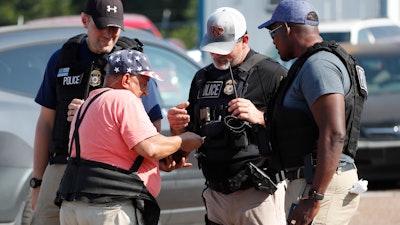 Domingo Candelaria, a registered immigrant, shows federal agents his identification as he prepares to leave the Koch Foods Inc., plant in Morton, Miss., following a raid by U.S. immigration officials, Wednesday, Aug. 7, 2019. The raid, one of several in Mississippi, was part of a large-scale operation targeting owners as well as undocumented employees.