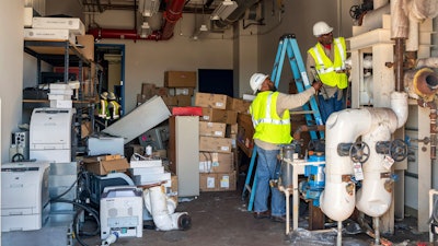 In this July 10, 2019 photo provided by the U.S. Navy, Department of Defense employees Matenis Bell and Andre Ledford, assigned to Naval Air Weapons Station China Lake, Calif., conduct building repairs after multiple earthquakes occurred July 4 and 5 in Kern County, Calif. The base sustained heavy earthquake damage that experts estimate will cost over $5 billion to repair.