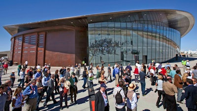 In this Oct. 17, 2011 file photo, guests stand outside the new Spaceport America hangar in Upham, N.M. Virgin Galactic is scheduled to unveil the interior of its digs at Spaceport America, providing the first glimpse of mission control, a prep area for pilots and where paying customers will lounge ahead of their suborbital flights. Company officials are gathering Thursday, Aug. 15, 2019, at the remote facility in the New Mexico desert to show off two levels of the custom-tailored hangar at the taxpayer-financed spaceport.