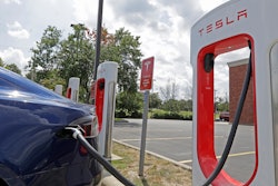 In this July 19, 2019 file photo, a Tesla vehicle charges at a Tesla Supercharger site in Charlotte, N.C. Tesla owners can now buy insurance policies from the electric car company in what may be an essential step toward it selling driverless vehicles. The company says it’s now selling policies in California and will go nationwide at an undisclosed date.