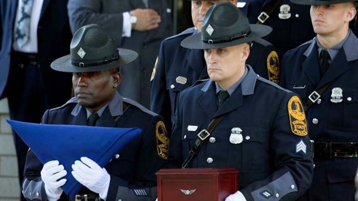 Virginia State Police carry a flag and remains of Trooper Berke Bates, who was killed in a helicopter crash during protests in Charlottesville, Va., at his funeral, Aug. 18, 2017.