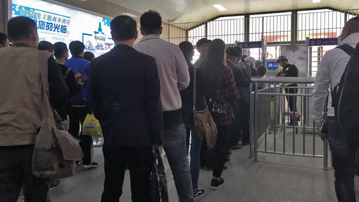 Uighurs wait in line at a face scan checkpoint in Turpan, Xinjiang in northwest China on April 11, 2018.
