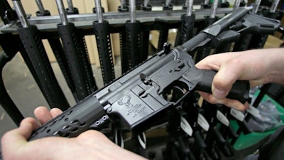 Craftsman Veetek Witkowski holds a newly assembled AR-15 rifle at the Stag Arms company in New Britain, Conn, Wednesday, April 10, 2013.