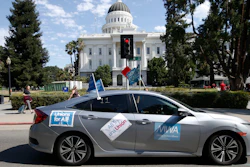 In this photo taken Aug. 28, 2019, a supporter of a measure to limit when companies can label workers as independent contractors drives past the Capitol during a rally in Sacramento.