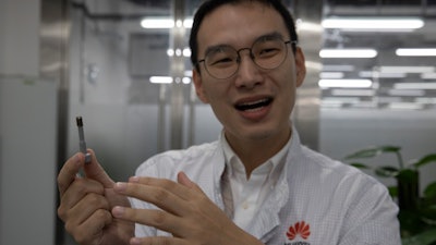 In this Aug. 21, 2019, photo, a Huawei research engineer holds up a coated screw, designed to reduce signal interference, at the Huawei Materials lab in Dongguan, China.