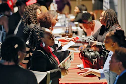 In this Aug. 14, 2019, file photo, representatives from Verizon, Goodwill, Kaiser Permanente and UPS talk with potential applicants during a job fair in Atlanta.