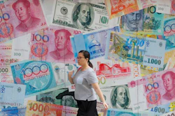 In this Aug. 6, 2019, file photo, a woman walks by a money exchange shop in Hong Kong.