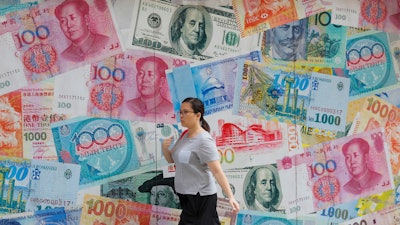 In this Aug. 6, 2019, file photo, a woman walks by a money exchange shop in Hong Kong.