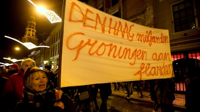 In this Jan. 19, 2018, file photo, a protester holds a banner reading 'The Hague Billions, Groningen To Shreds' as thousands of people protest against gas extraction and related earthquakes.