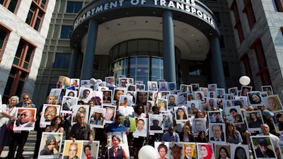 Demonstrators hold pictures of the plane crash victims during a vigil outside of the Department of Transportation in Washington, Tuesday, Sept. 10, 2019.