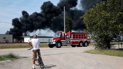 A resident watches as a firetruck arrives in downtown Dupo, Ill. to help fight a tanker fire, Tuesday, Sept. 10. 2019.