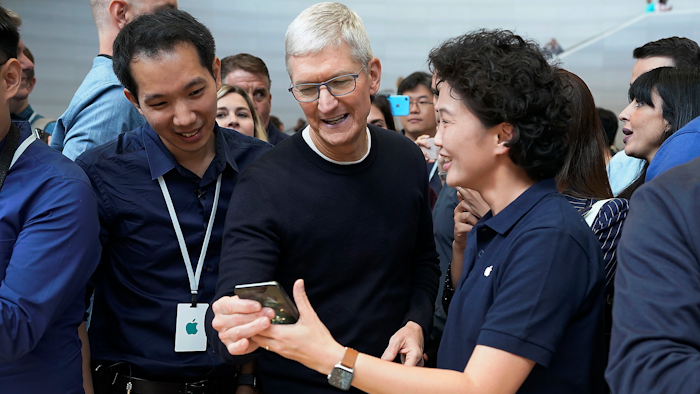 Apple CEO Tim Cook, center, looks at the the new iPhone 11 Pro Max during an event to announce new products Tuesday, Sept. 10, 2019, in Cupertino, Calif.