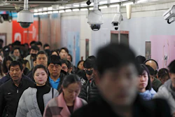 In this Feb. 26, 2019, file photo, commuters walk by surveillance cameras installed at a walkway in between two subway stations in Beijing.