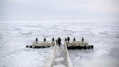 In this image taken Feb. 9, 2012, tourists admire the frozen IJsselmeer inland sea on Afsluitdijk, a dike closing off the Wadden sea and North Sea from IJsselmeer inland sea, northern Netherlands.