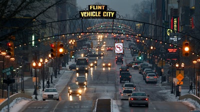 In this Jan. 21, 2016, file photo, vehicles drive through downtown Flint, Mich.