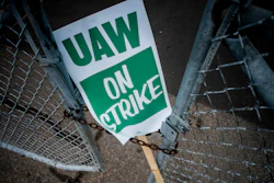 In this Monday, Sept. 16, 2019, file photo, a United Auto Workers strike sign rests between the chains of a locked gate entrance outside of Flint Engine Operations in Flint, Mich.