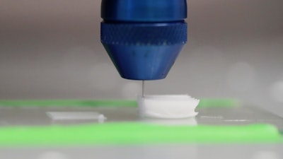 Printer head on a solvent-cast 3D printer depositing the functionalized polymer inks layer-by-layer from a needle. The solvent evaporates, leaving behind a solid 3D-printed polymer fiber.