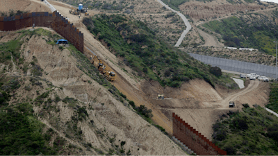 In this March 11, 2019 photo, construction crews replace a section of the primary wall separating San Diego, above right, and Tijuana, Mexico, below left, seen from Tijuana, Mexico. Defense Secretary Mark Esper has approved the use of $3.6 billion in funding from military construction projects to build 175 miles of President Donald Trump’s wall along the Mexican border.