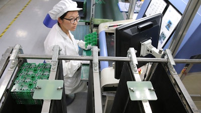 In this Aug. 27, 2019, photo, an employee works on the production line of a smart electricity meter manufacturing plant in Nantong in eastern China's Jiangsu province. Two surveys of Chinese manufacturing show demand is weak amid a mounting tariff war with Washington over trade and technology.