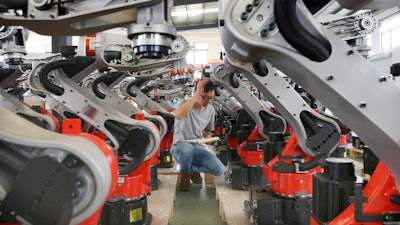 In this Wednesday, Sept. 11, 2019, photo, a man checks on the robotic arms at a factory making industrial robots in Zhengyu town of Haimen city in east China's Jiangsu province. A Chinese envoy is going to Washington on Wednesday, Sept. 18, to prepare for trade negotiations. The announcement Tuesday, Sept. 17, follows conciliatory gestures by both sides ahead of the October talks on their fight over trade and technology, which threatens to dampen global economic growth.