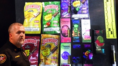 Sgt. Christopher Hannah of the Kenosha County Sheriff's Department stands in front of a display of the colorfully packaged vaping products during a news conference in Kenosha Wednesday, Sept. 11, 2019.