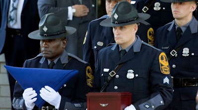 Virginia State Police carry a flag and remains of Trooper Berke Bates, who was killed in a helicopter crash during protests in Charlottesville, Va., at his funeral, Aug. 18, 2017.