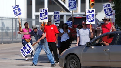 Gary Allison, left, waves while standing with other union members picketing outside the General Motors Plant in Arlington, Texas, Monday, Sept. 16, 2019. More than 49,000 members of the United Auto Workers walked off General Motors factory floors or set up picket lines as contract talks with the company deteriorated into a strike.