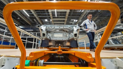 In this Tuesday, May 14, 2019 file photo, Heiko Roesch, head of body construction, walks besides the new electric 'ID.3' car body during a press tour at the plant of the German manufacturer Volkswagen AG (VW) in Zwickau, Germany. Volkswagen is rolling out what it bills as the breakthrough electric car for the masses, the leading edge of a wave of new battery-powered vehicles about to hit the European auto market. The ID.3 is going on display ahead of the Frankfurt Motor Show on Monday Sept. 9, 2019.