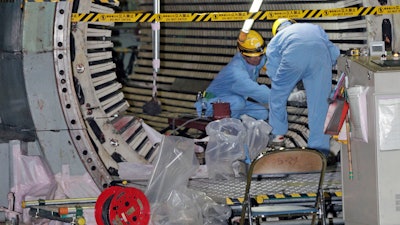 In this Nov. 28, 2018, photo, workers dismantle the Unit 2 reactor at Chubu Electric Power Co.,'s Hamaoka nuclear power plant in Omaezaki, Shizuoka prefecture. Japan's nuclear policy-setting body has adopted a report saying the country is entering an era of massive nuclear plant decommissioning, urging operators to plan ahead to lower safety risks and costs on work requiring decades and billions of dollars.
