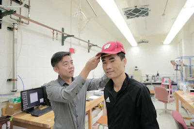 UW-Madison Materials Science and Engineering Professor Xudong Wang (left) and colleagues developed an device -- unobtrusive enough to fit under a cap -- that harnesses energy from the wearer and delivers gentle electric pulses to stimulate dormant hair follicles and regrow hair.