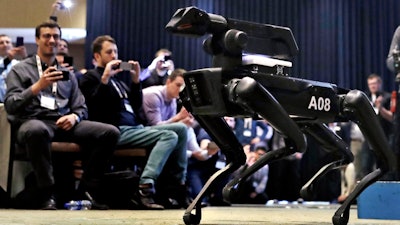 In this May 24, 2018, file photo, a Boston Dynamics SpotMini robot is walks through a conference room during a robotics summit in Boston. The Cirque du Soleil Entertainment Group says it’s in talks with robot-maker Boston Dynamics about using the four-legged Spot robot in its live shows.