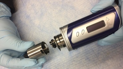 Photo of a typical tank-style electronic cigarette. With the lid off, the atomizer attached to the tank is revealed.