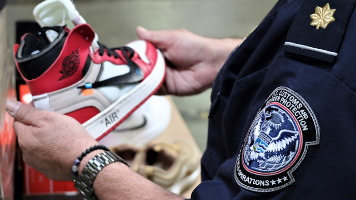 This undated photo shows an agent holding one of more than 14,800 pair of counterfeit Nike shoes, seized in a shipment arriving from China at the Los Angeles-Long Beach sports complex.
