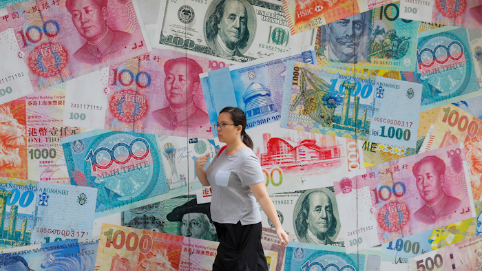 In this Aug. 6, 2019, file photo, a woman walks by a money exchange shop in Hong Kong.