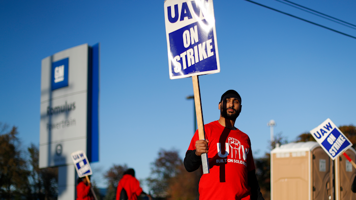 In this Oct. 9, 2019, file photo, a member of the United Auto Workers walks the picket line at the General Motors Romulus Powertrain plant in Romulus, Mich.