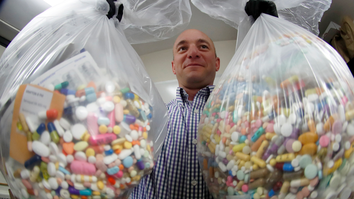 In this Sept. 11, 2019, file photo, narcotics detective Ben Hill of the Barberton Police Department shows two bags of medications stored in their headquarters.