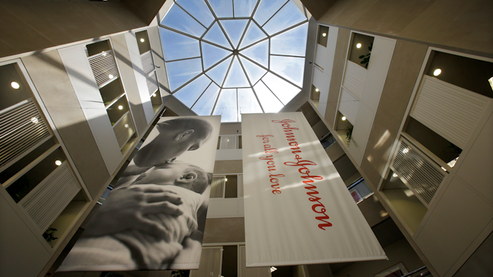 In this July 30, 2013, file photo, large banners hang in an atrium at the headquarters of Johnson & Johnson in New Brunswick, N.J. Johnson & Johnson has agreed to a $117 million multistate settlement over allegations it deceptively marketed its pelvic mesh products, which support women's sagging pelvic organs.